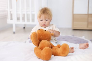 Yatakta oyuncaklarla oynayan tatlı bir bebek.