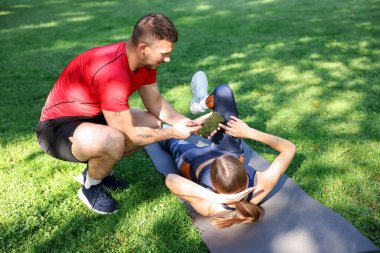 Dışarıda profesyonel antrenörle egzersiz yapan genç bir kadın.