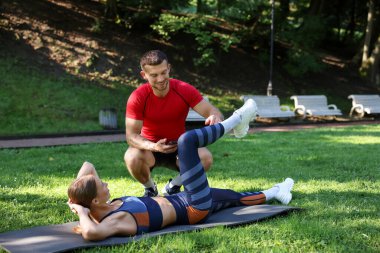 Dışarıda profesyonel antrenörle egzersiz yapan genç bir kadın.