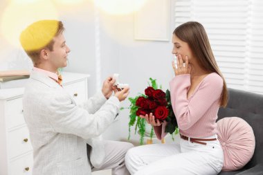 Nişan yüzüğü ve gül buketi olan bir adam evde duygusal kız arkadaşına evlenme teklif ediyor. Bokeh etkisi