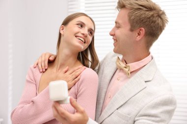 Evlilik teklifi. Nişan yüzüğüyle gülümseyen adam ve evde mutlu kız arkadaşı.