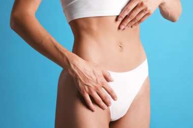 Açık mavi arka planda düz göbekli kadın, yakın plan.