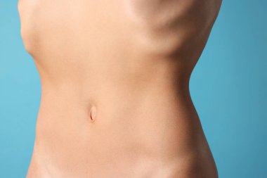 Açık mavi arka planda düz göbekli kadın, yakın plan.