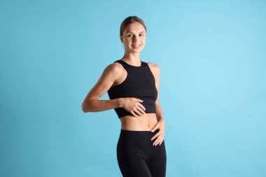 Açık mavi arka planda düz göbekli bir kadın.