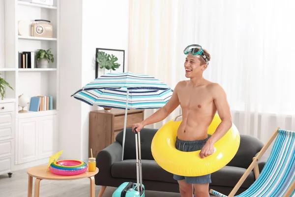 Dalış maskesi, bavulu ve şişme yüzüğü olan mutlu bir adam. Denizde tatilin hayalini kuruyorum.