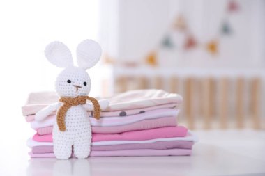 Temiz bebek kıyafetleri ve aksesuar yığını beyaz masa içinde, yakın plan.