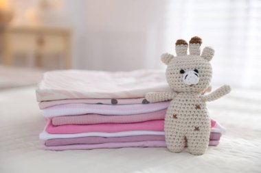 Temiz bebek kıyafetleri ve yatak örtüleri iç mekanda, yakın plan.