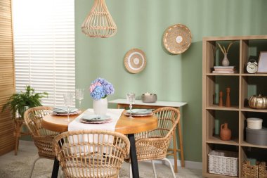 Yemek odasındaki ahşap masada, tabak ve vazo çiçekli şık bir ortam. İç tasarım