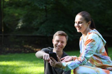 Profesyonel antrenörü olan genç bir adam açık havada telefona bakıyor. Metin için boşluk