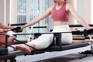 Stüdyoda pilates eğitmeni tarafından denetlenen reformcu kadın, yakın plan.