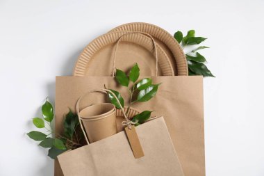 Farklı çevre dostu paketleme, sofra takımı ve beyaz arkaplanda yapraklar, düz uzanma