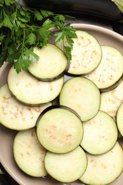 Tahta masada taze patlıcan ve maydanoz dilimleri, düz uzanmış.