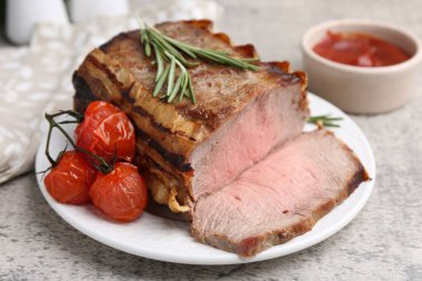 Lezzetli pişmiş et, domates, biberiye ve sos gri masada, yakın plan.