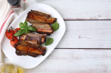 Kızarmış sığır kaburgası, domates ve baharatlar beyaz ahşap masa üzerinde, düz yatak. Metin için boşluk