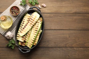 Lezzetli ızgara kabak dilimleri fırın kabında, yağ ve baharatlar ahşap masada, düz bir şekilde. Metin için boşluk