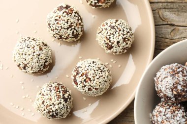 Fındıklı çikolata şekerler, susam tohumları ve ahşap masada hindistan cevizi taneleri.