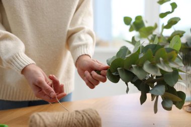 Çiçekçi dükkanındaki ahşap masada güzel okaliptüs dalları yapan bir makara ipliği olan çiçekçi.
