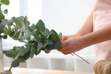 Çiçekçi çiçekçide okaliptüs dallarından güzel bir buket yapıyor, yakın plan.