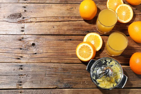 Taze sıkılmış portakal suyu, meyve suyu ve meyve sıkacağı ahşap masada, düz yerde. Metin için boşluk