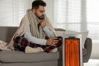 Evdeki koltukta elini ısıtan adam.