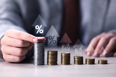 Masaya para istifleyen adam, yakın plan. Yığınların üzerinde yüzdelik işaretleri ve oklar