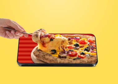 Yemek siparişi ve teslimat servisi. Kadın, portakal rengi arka planda cep telefonu ekranından lezzetli bir dilim pizza alıyor.