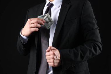 Adam siyah arka plana dolar koyuyor, yakın plan.