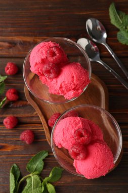Tatlı kaselerinde nefis ahududu şerbeti, kaşıklar, nane ve taze böğürtlen ahşap masada, düz uzanmış