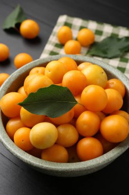 Olgun sarı kiraz erikleri Siyah ahşap masa üzerinde yapraklar, yakın çekim