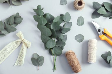 Çiçekçi. Okaliptüs dalları, iplikler, budama ve beyaz masanın üzerinde düz bir şekilde yatar.