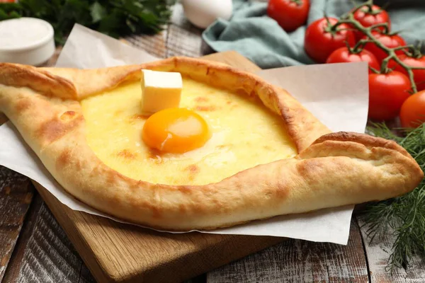 Lezzetli khachapuri peyniri, yumurtası ve diğer ürünleri ahşap masada, yakın plan.
