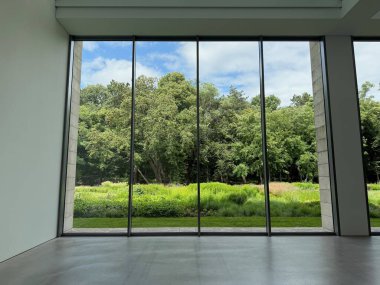 Güzel yeşil ağaçlar ve mavi gökyüzünün altındaki diğer farklı bitkiler, panoramik pencerelerden bakıyorlar.