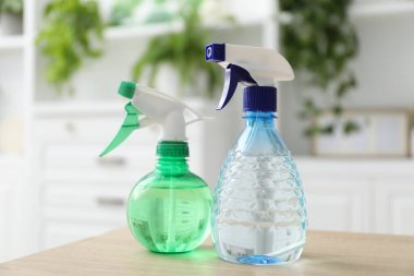 Çiçek bakımı. Ahşap masada iki sprey boya şişesi, yakın plan.