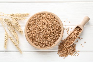 Kasede buğday taneleri, beyaz ahşap masada kepçeler ve çiviler, düz uzanmış