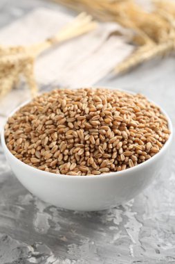 Kasede buğday taneleri ve gri masada çiviler, yakın plan.