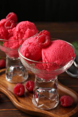 Tatlı kaselerinde nefis ahududu şerbeti ve ahşap masada siyah arka planda taze böğürtlen, yakın plan.