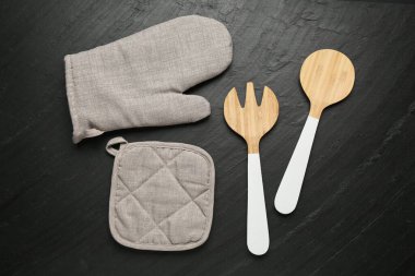 Gri fırın eldiveni ve diğer mutfak gereçleri koyu dokulu masa üzerinde, düz yatıyordu.