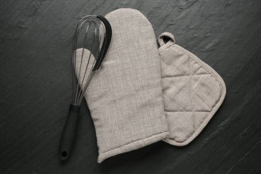 Gri fırın eldiveni, tutkal ve koyu dokulu masa üzerinde çırpma, düz uzanma