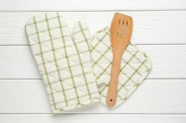 Fırın eldiveni, tutucu ve beyaz ahşap masa üzerinde spatula, düz yatıyordu.