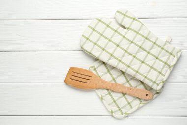 Fırın eldiveni, tutacağı ve beyaz ahşap masa üzerinde spatula, düz yatak. Metin için boşluk