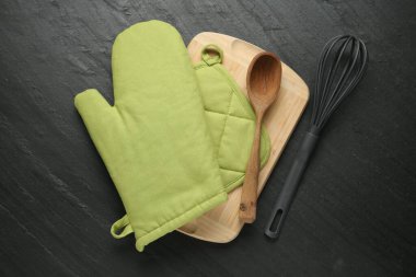 Yeşil fırın eldiveni, ahşap kaşık, tutucu, koyu dokulu masa üzerinde çırpı ve yiyecek, düz uzanma