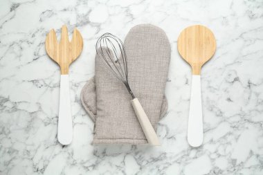 Fırın eldiveni, tutkal ve diğer mutfak gereçleri beyaz mermer masa, düz yatıyordu.