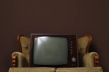 Kahverengi duvarın yanındaki kanepede televizyon var, mesaj için yer var. Kullanılmış eşyalar