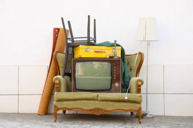 Kanepede televizyon ve beyaz duvarın yanında kullanılan diğer şeyler.