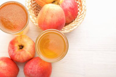 Bardakta nefis elma şarabı ve beyaz ahşap masada kırmızı elmalar, düz yatak. Metin için boşluk