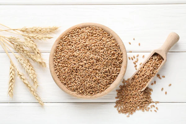 Kasede buğday taneleri, beyaz ahşap masada kepçeler ve çiviler, düz uzanmış