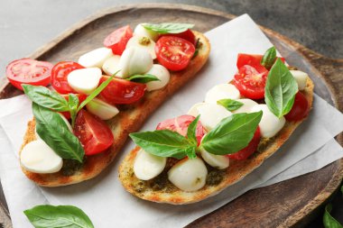 Peynirli, domatesli ve fesleğenli lezzetli sandviçler. Gri desenli masa, yakın plan.