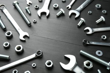 Siyah ahşap masanın üstünde birçok metal anahtar, cıvata ve ceviz var. Metin için boşluk