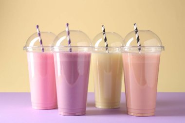 Renkli arka planda plastik bardaklarda lezzetli milkshake.