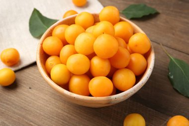 Olgun sarı kiraz erikleri ve yapraklar ahşap masada, yakın plan.